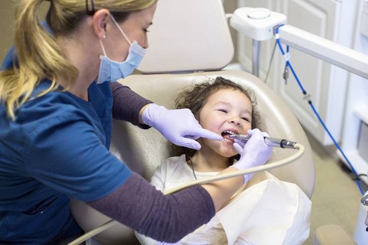 Pediatric dentist examining young child's teeth during sedation dentistry appointment in Delray Beach.